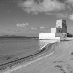 Black and white image of a historic beach tower in Trapani, Sicily with sweeping ocean views.